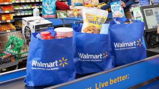 Photo of three full recyclable grocery bags with the Walmart logo on checkout counter.