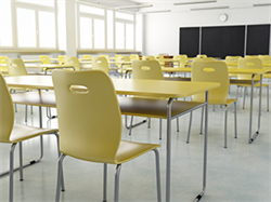 Empty classroom with rows of tables and chairs facing a blackboard.