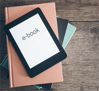 Photo of ebook on a pile of books.