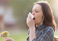 Woman sneezing into kleenex tissue.
