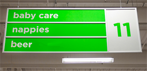 Aisle sign in department store ceiling listing baby care, nappies, and beer