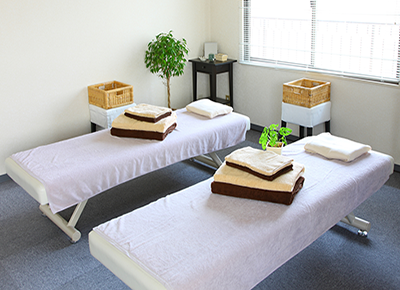Room interior with 2 massage tables, each with pillows and several folded towels.