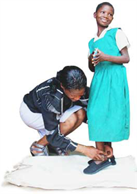 Woman buckling a young girl's shoe.