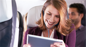 Passenger in airplane seat viewing iPad.