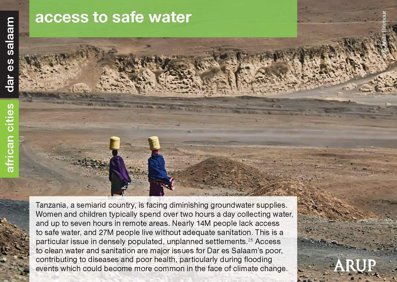 two young men carry water on their heads near a dry river bed