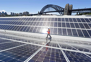 construction worker walking between solar panels on large rooftop