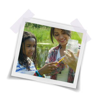 Girl and her teacher making a prediction about something in a jar.