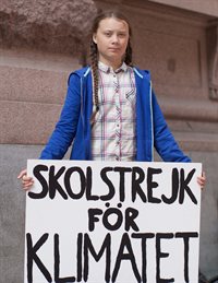 Greta Thunberg holds a sign reading "Skolstrejk för Klimatet" (School strike for climate")