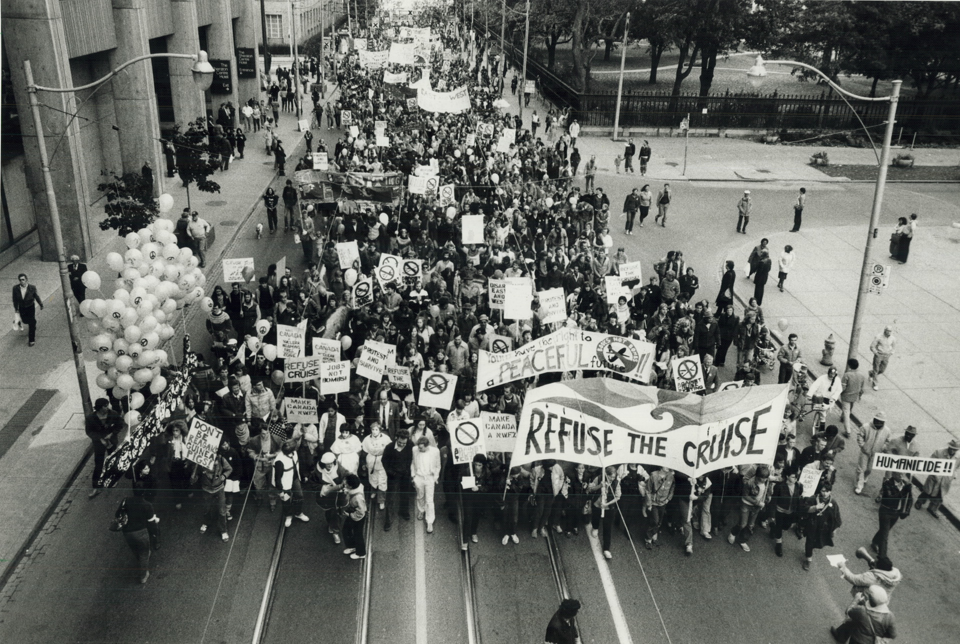 Crowd of protestors fills the streets, holding signs reading 'refuse the cruise'