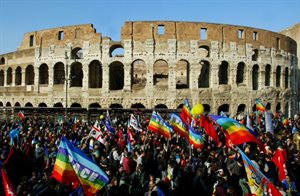 Large group of protestors wave Peace flags outside Coliseum in Rome