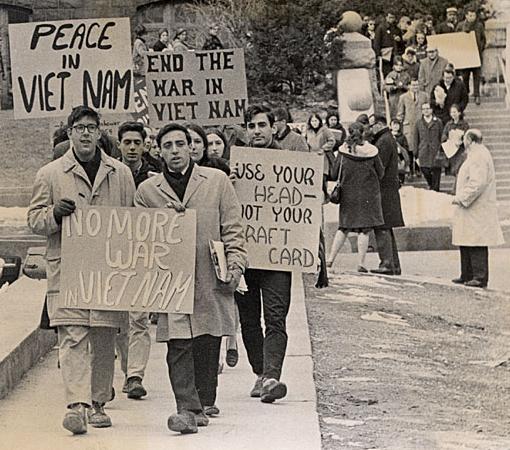 Students marching holding signs reading "No more war in vietnam", "Peace in Vietnam", and "Use your head - not your draft card"